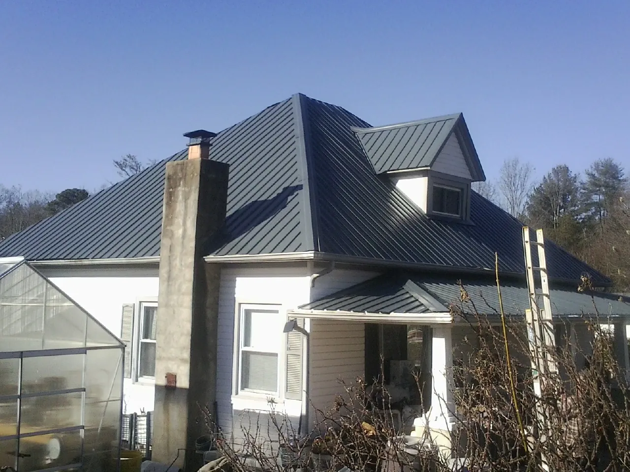 Dark blue standing seam metal roof on a white farmhouse with dormer — Slate & Tile Roof Repair by Roofing Brothers in Oaks