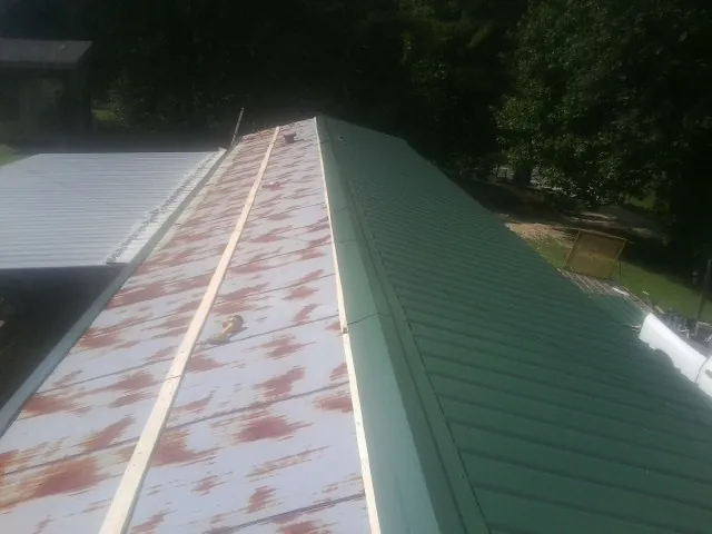 Old rusted panels beside newly installed green metal roofing — Wind Damage Roof Repair by Roofing Brothers in Oaks