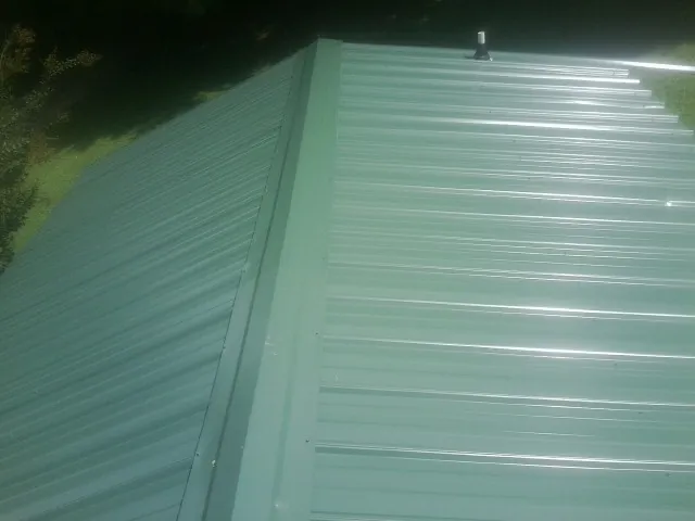 New green metal panels meeting at the ridge of a roof — Flat Roof Repair work by our crew in Oaks
