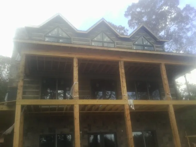 Dormers and porch framing on a large log home under construction — Roof Coating work by our crew in Oaks