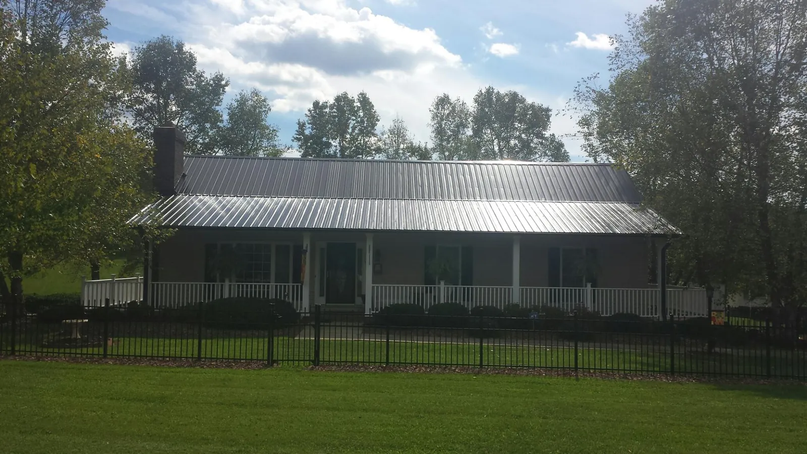 Gray metal roof on a brick ranch with a full width front porch — Gutter Guard Installation work by our crew in Oaks