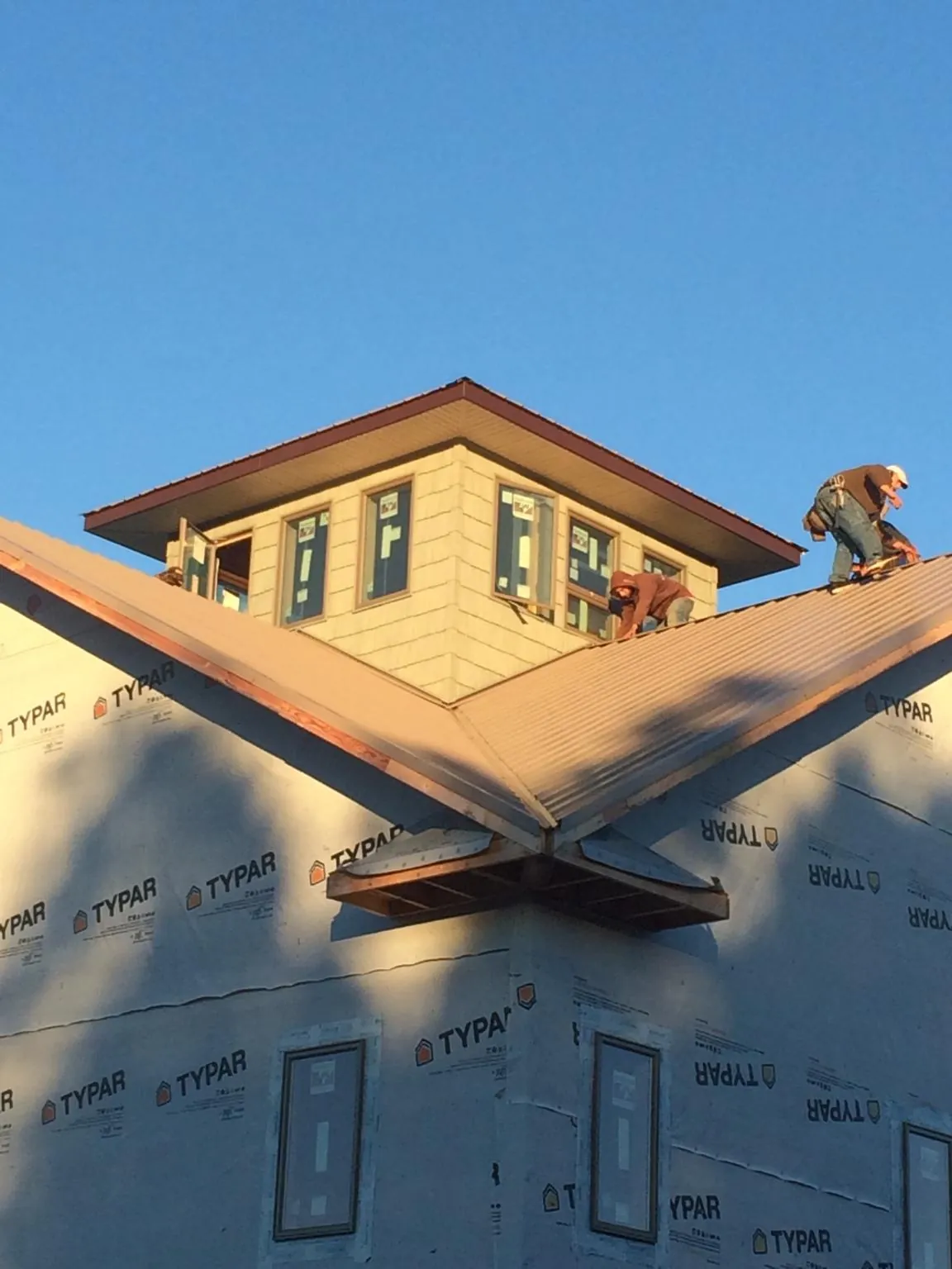 Roofers working around a rooftop cupola on a new metal roof at sunset — Roof Waterproofing in Oaks by Roofing Brothers